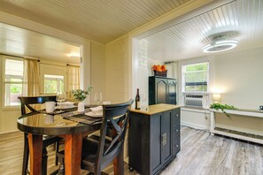 A dining area with a round table, chairs, a cabinet, and a window with blinds.