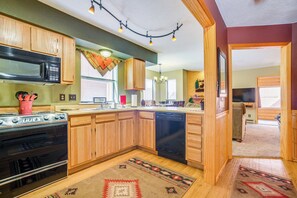 A kitchen with wooden cabinets, a microwave, an oven, and a dishwasher. - Walk to Angel Fire Resort! Mtn-view Condo Near Fun (Angel Fire)