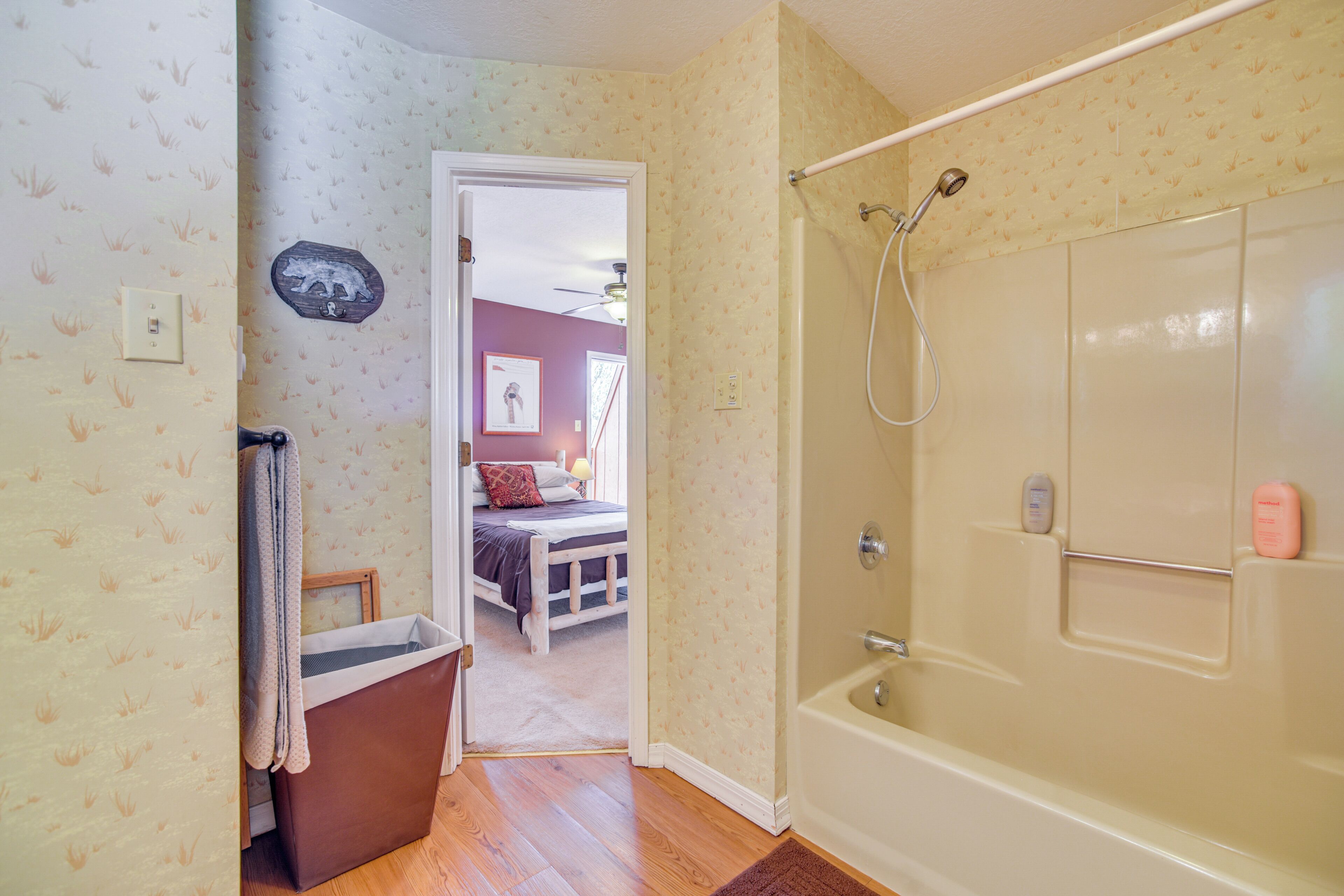 Un baño con bañera, ducha y una puerta visible que da a un dormitorio.