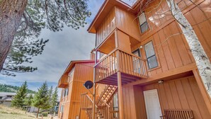 Un bâtiment en bois à plusieurs étages, doté d’un balcon, d’un escalier et d’un banc.