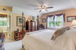 A bedroom with a bed, dresser, and window with curtains.