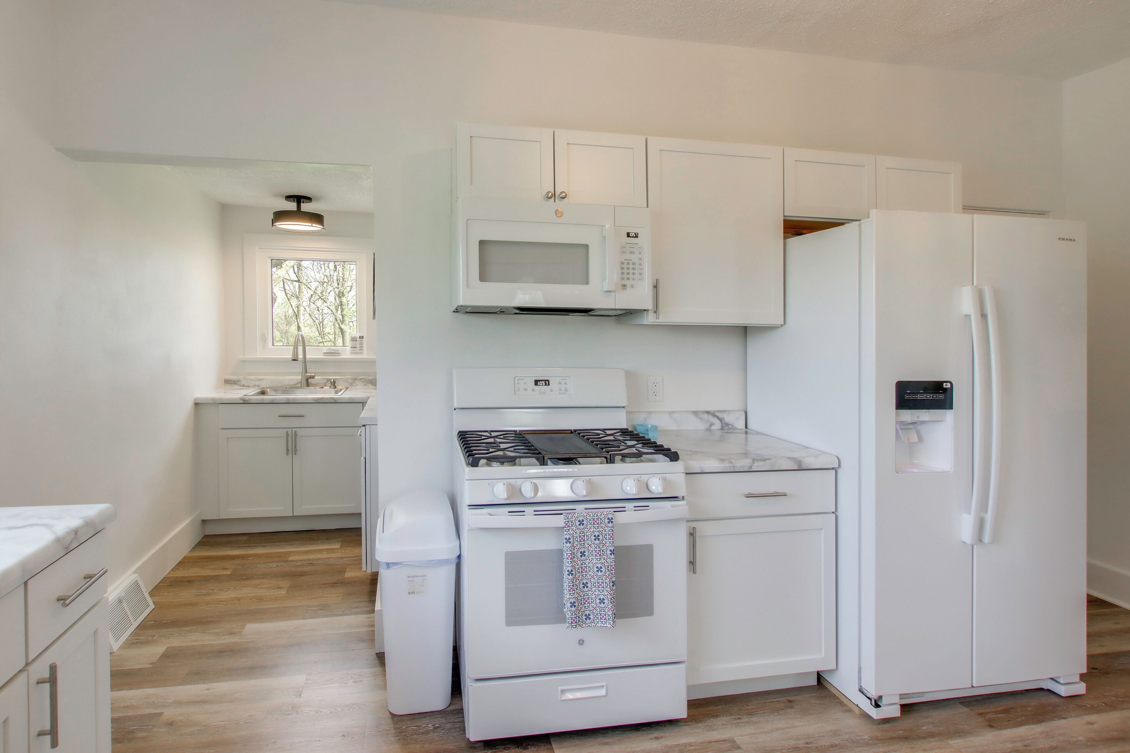 A kitchen with white cabinets, a microwave, a stove, and a refrigerator.