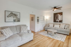 A modern living room with a grey sofa, a coffee table, and a ceiling fan.