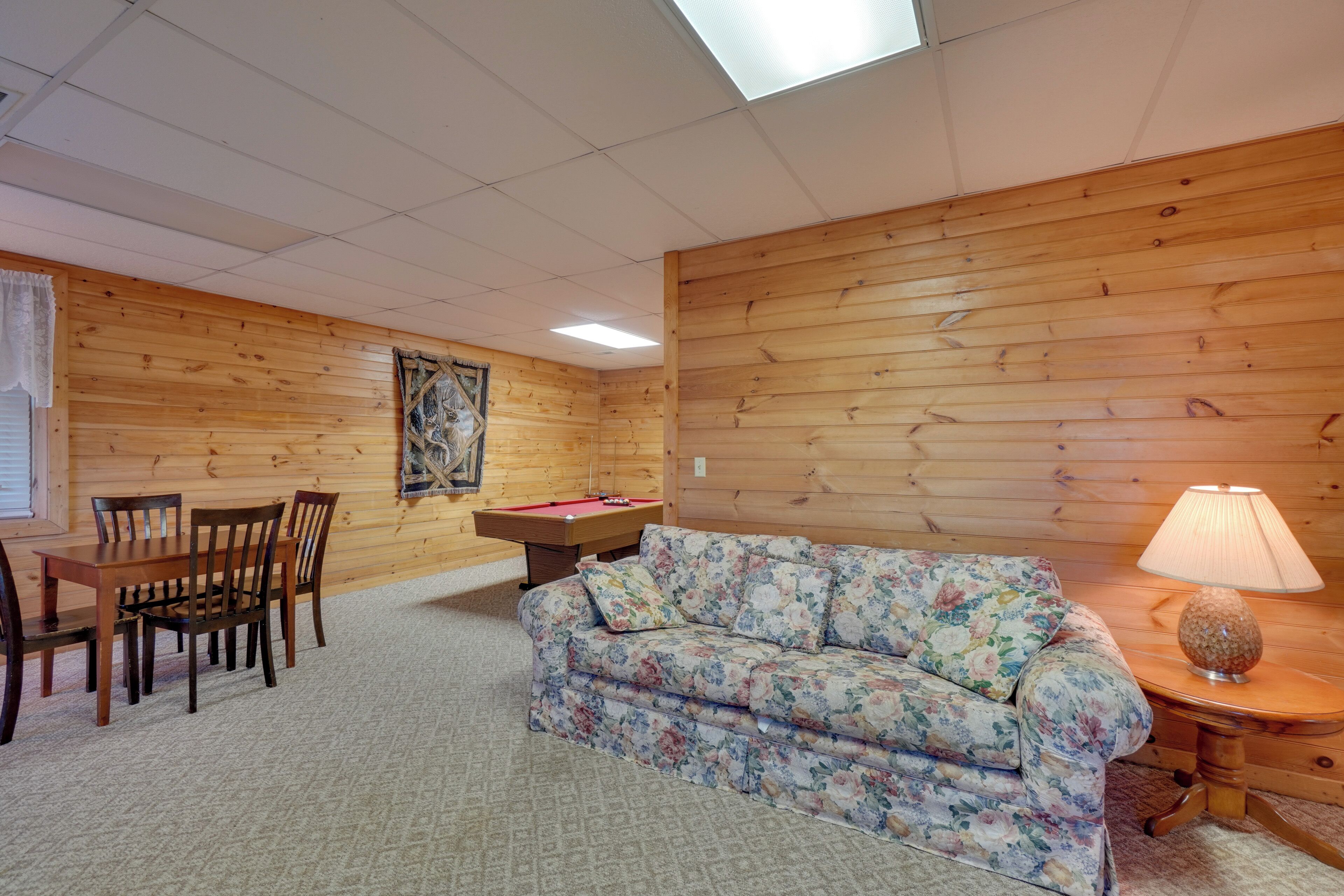 Ein Zimmer mit Holzwänden, einer Couch, einem Tisch und Stühlen.