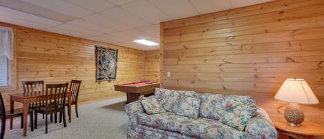 Ein Zimmer mit Holzwänden, einer Couch, einem Tisch und Stühlen.