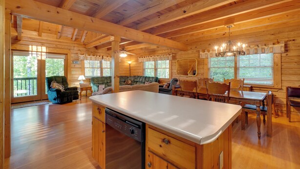 A wooden cabin interior with a kitchen island, dining table, and chairs. - Wooded Cabin w/ Decks & Dale Hollow Lake Views! (Byrdstown)