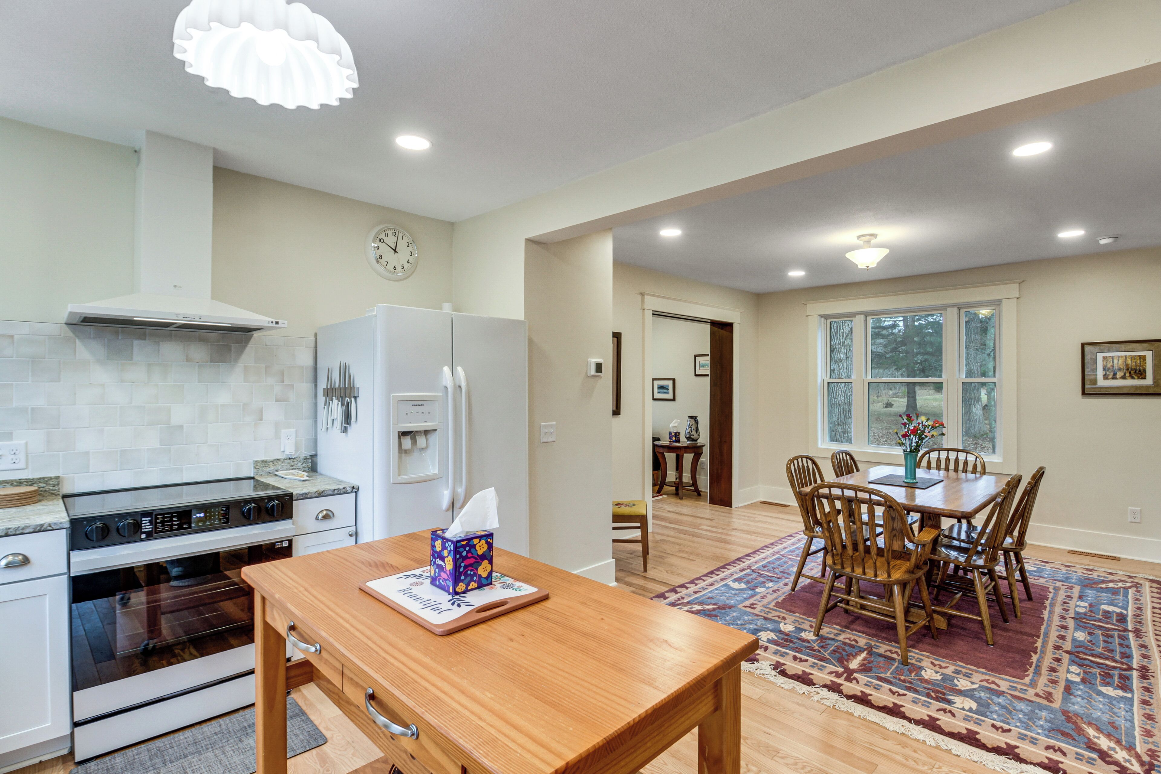 A kitchen with modern appliances, a dining area with a table and chairs, and a large window.