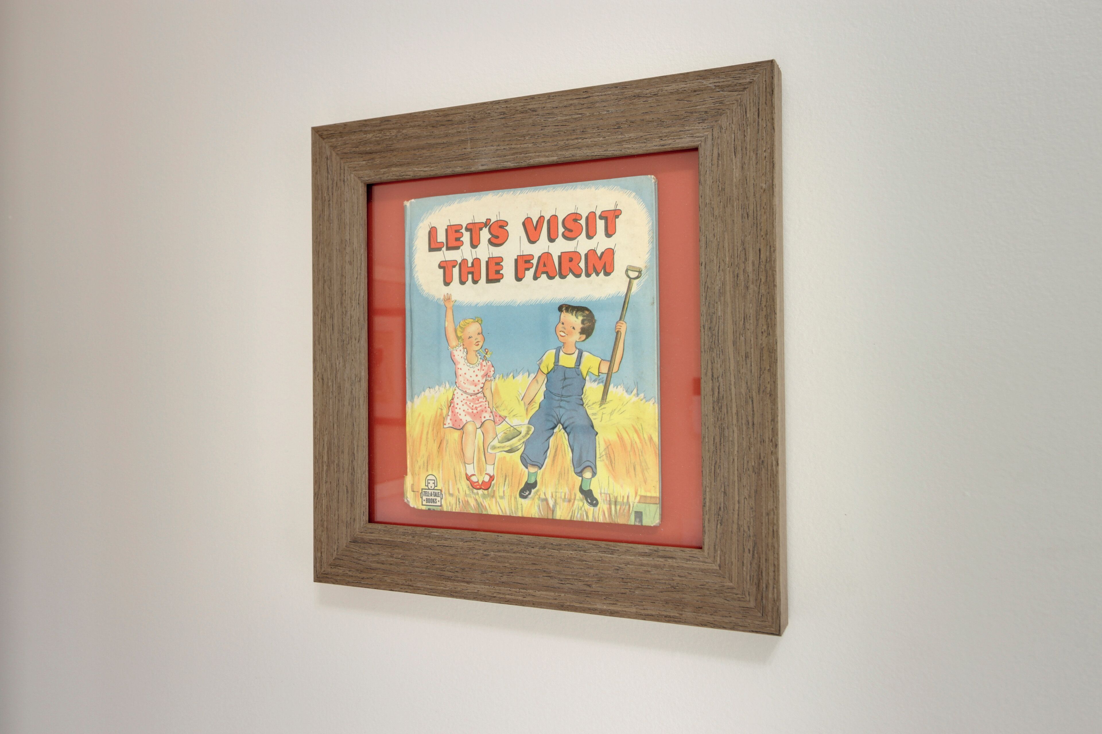 A framed picture with a farm visit theme, featuring two children and a farm tool.