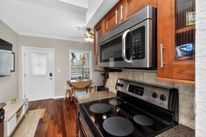 A kitchen with a stainless steel microwave, a stove, and wooden cabinets.