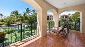Ein Balkon mit Blick auf einen angelegten Garten und ein Gewässer.