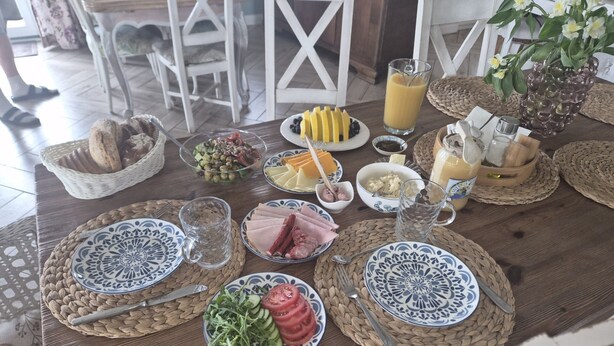 Una mesa de desayuno con platos de comida, un vaso de jugo y un tazón de ensalada.