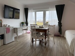 Ein Zimmer mit Esstisch, Stühlen, einem an der Wand montierten Fernseher und einem Bett.