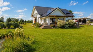 Una casa de dos pisos con techo de paneles solares, garaje cubierto y césped bien cuidado.
