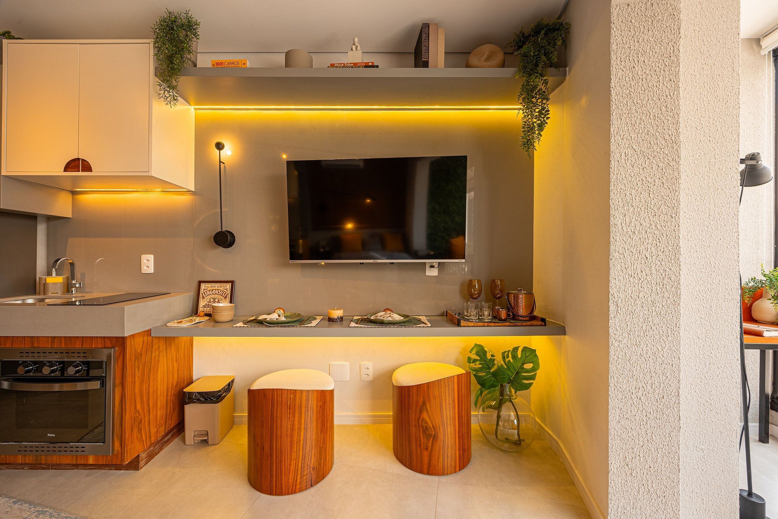 A modern kitchen with a built-in oven, a sink, and two stools.