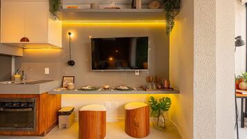 A modern kitchen with a built-in oven, a sink, and two stools.