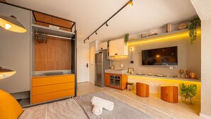 Una habitación de hotel moderna con cama, escritorio, kitchenette y televisión.
