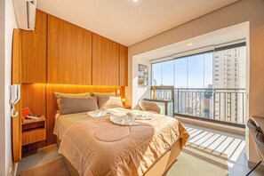 Une chambre moderne avec un grand lit, une armoire en bois et un balcon offrant une vue sur la ville.