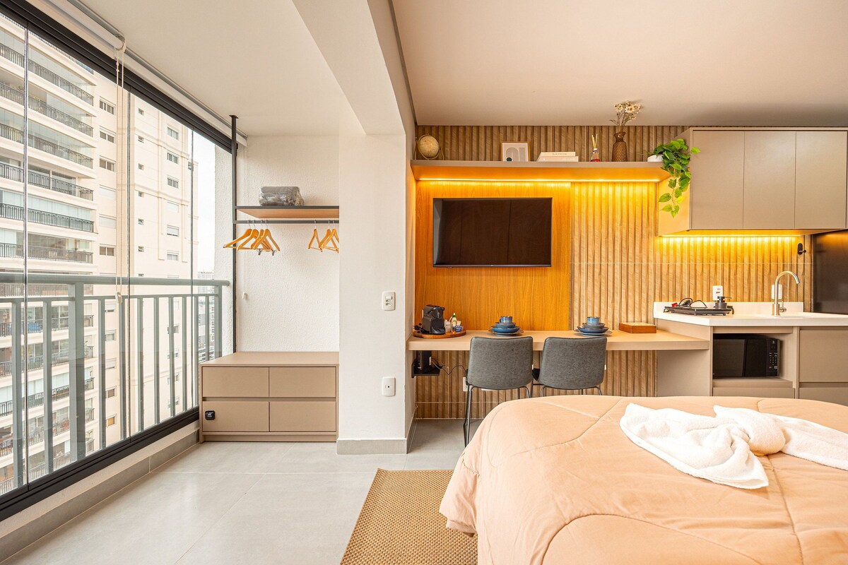 Une chambre d’hôtel moderne dotée d’un grand lit, d’un bureau avec un ordinateur, d’une télévision à écran plat et offrant une vue sur la ville grâce à de grandes fenêtres du sol au plafond.