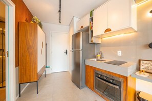 Una cocina moderna con horno empotrado, refrigerador de acero inoxidable y muebles de madera.
