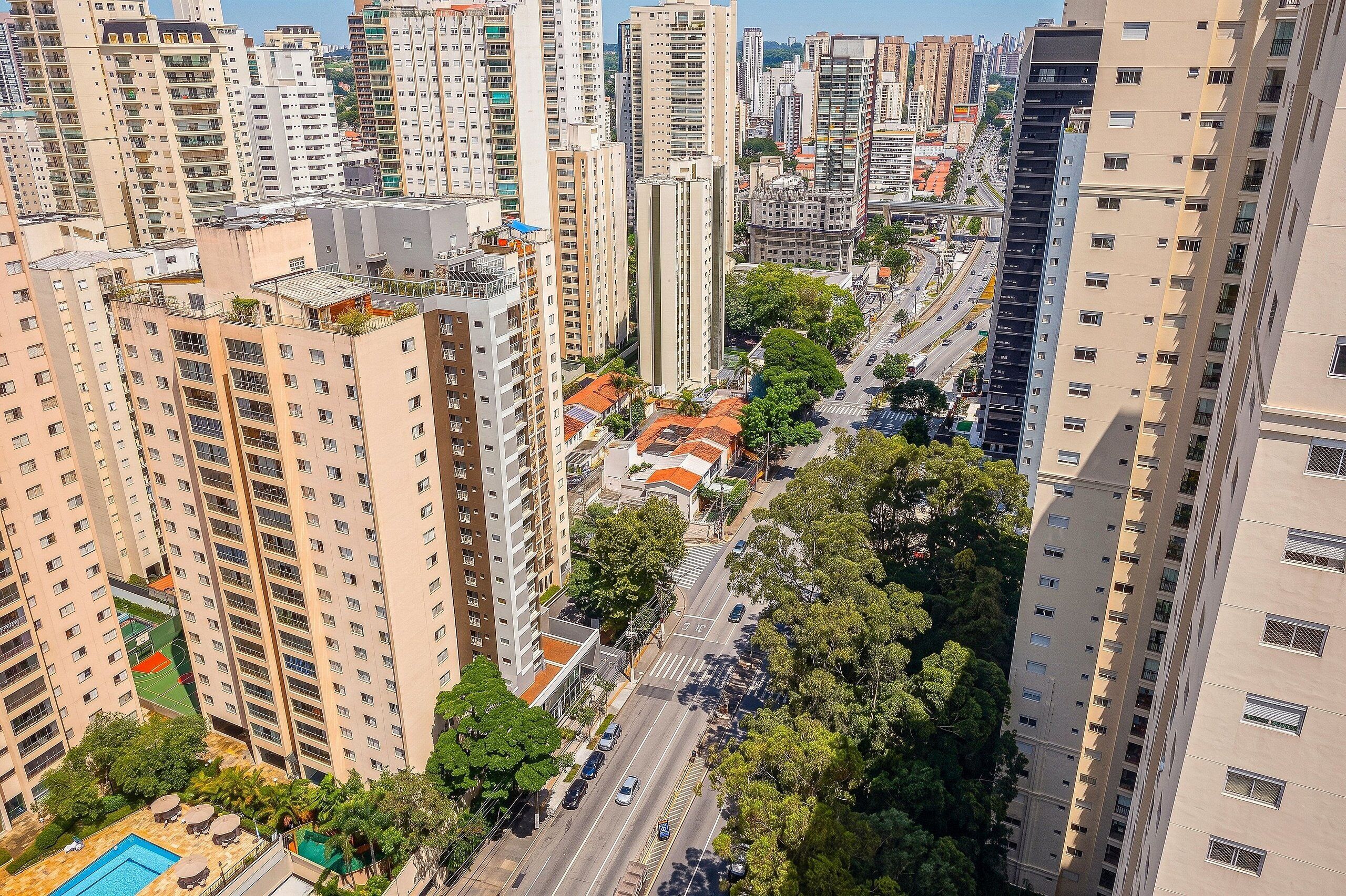 A high-rise urban area with multiple buildings, a street with cars, and trees.