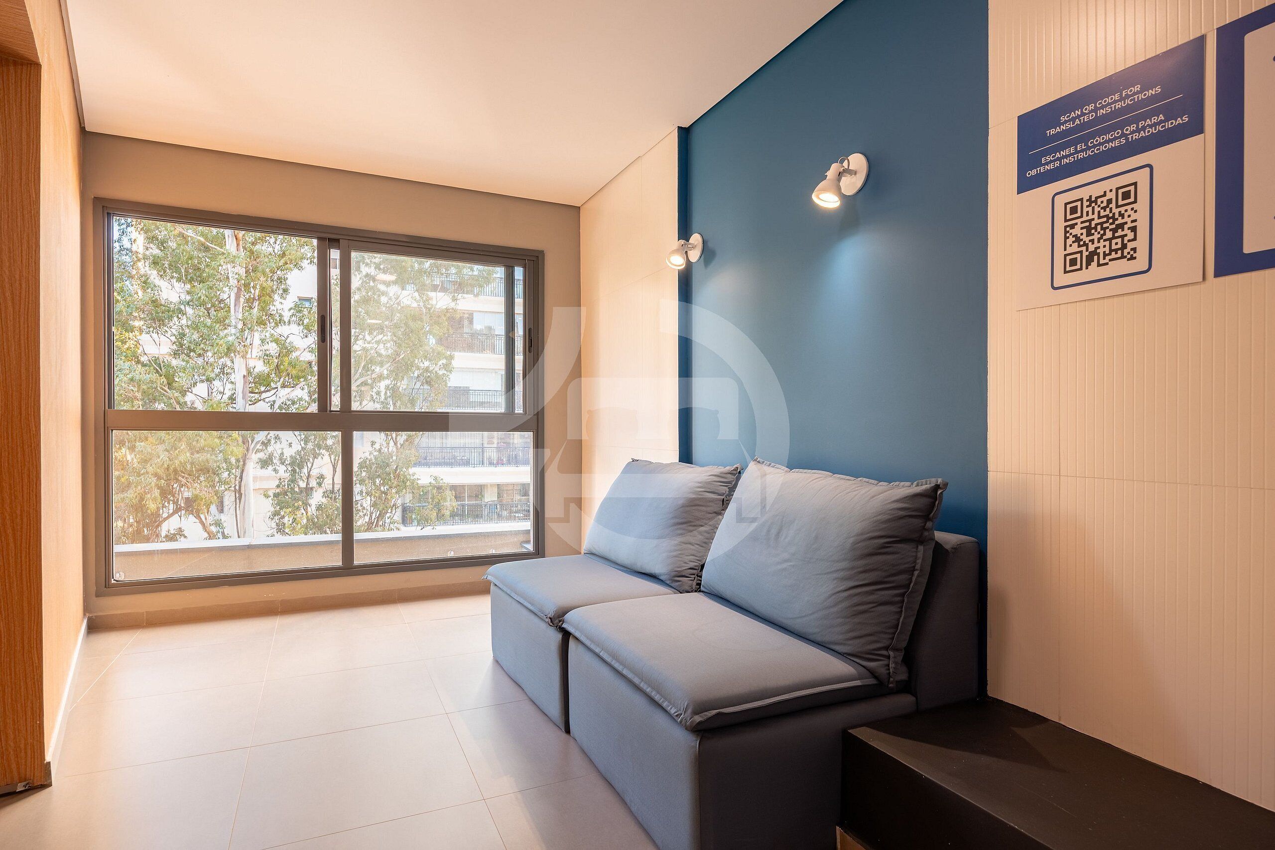 A modern room with a large window, a sofa, a wall-mounted light, and a QR code for instructions.