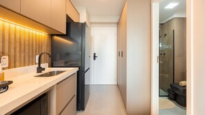 A modern kitchen with a built-in dishwasher, a black refrigerator, and a countertop with a sink. - Hospedez - Estudios Campo Belo Movi (São Paulo)