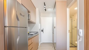 Cocina estrecha con refrigerador de acero inoxidable, armarios de madera y una puerta blanca al final.