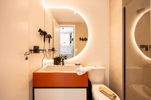 Une salle de bain moderne avec un grand miroir, un lavabo et des toilettes.