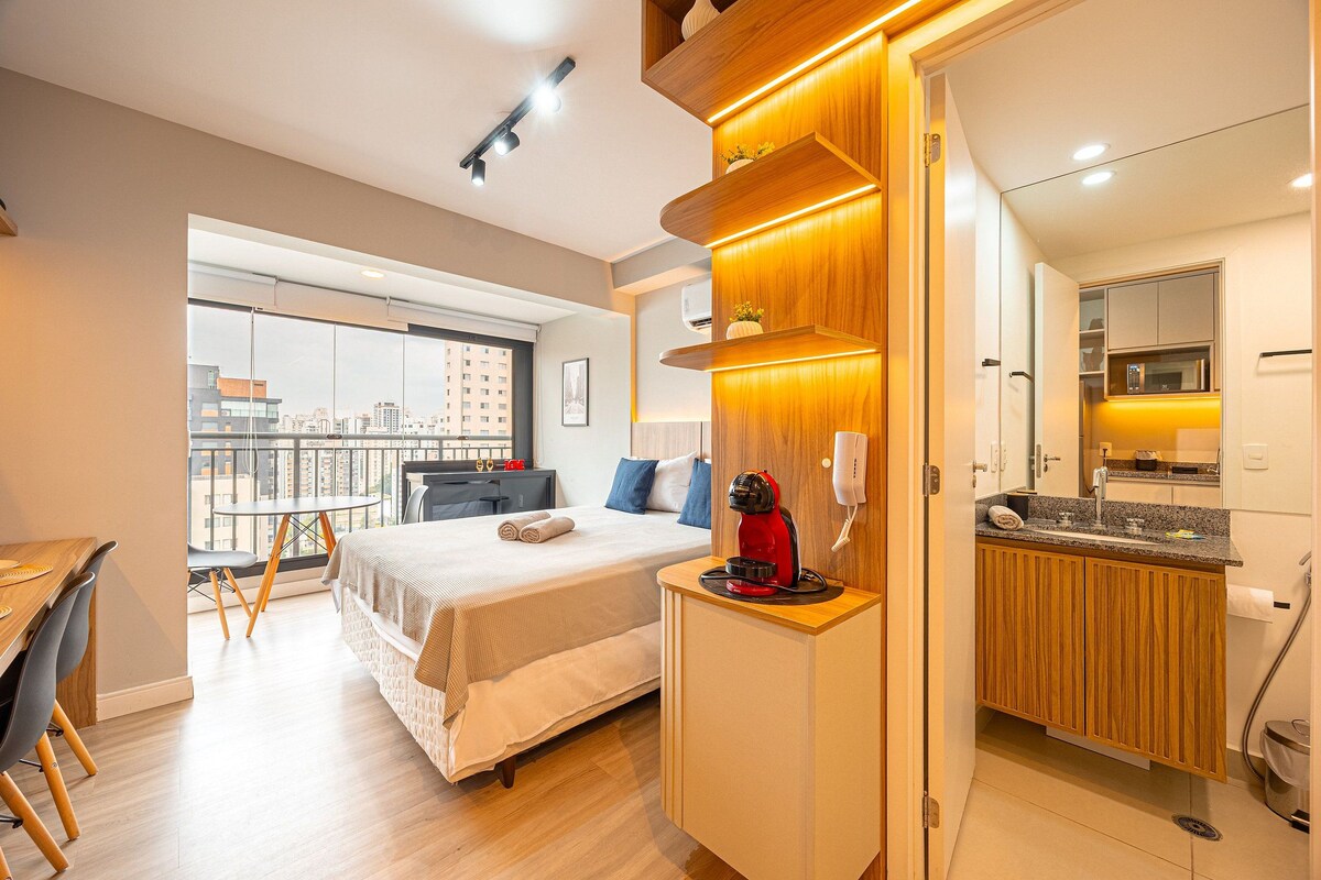 A modern hotel room with a bed, bedside table, and a view of the city.