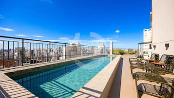 Ein Pool auf dem Dach mit freiem Blick auf die Stadt, einer Brüstung und Sitzgelegenheiten im Freien.