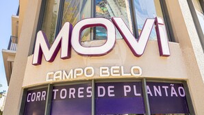 Un edificio con un gran letrero que dice 'MOVI CAMPO BELO' y 'CORR TORES DE PLANTÃO'.