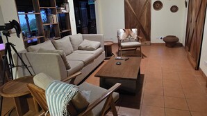 Un amplio salón con techo alto, un sofá, una mesa de centro y una silla.