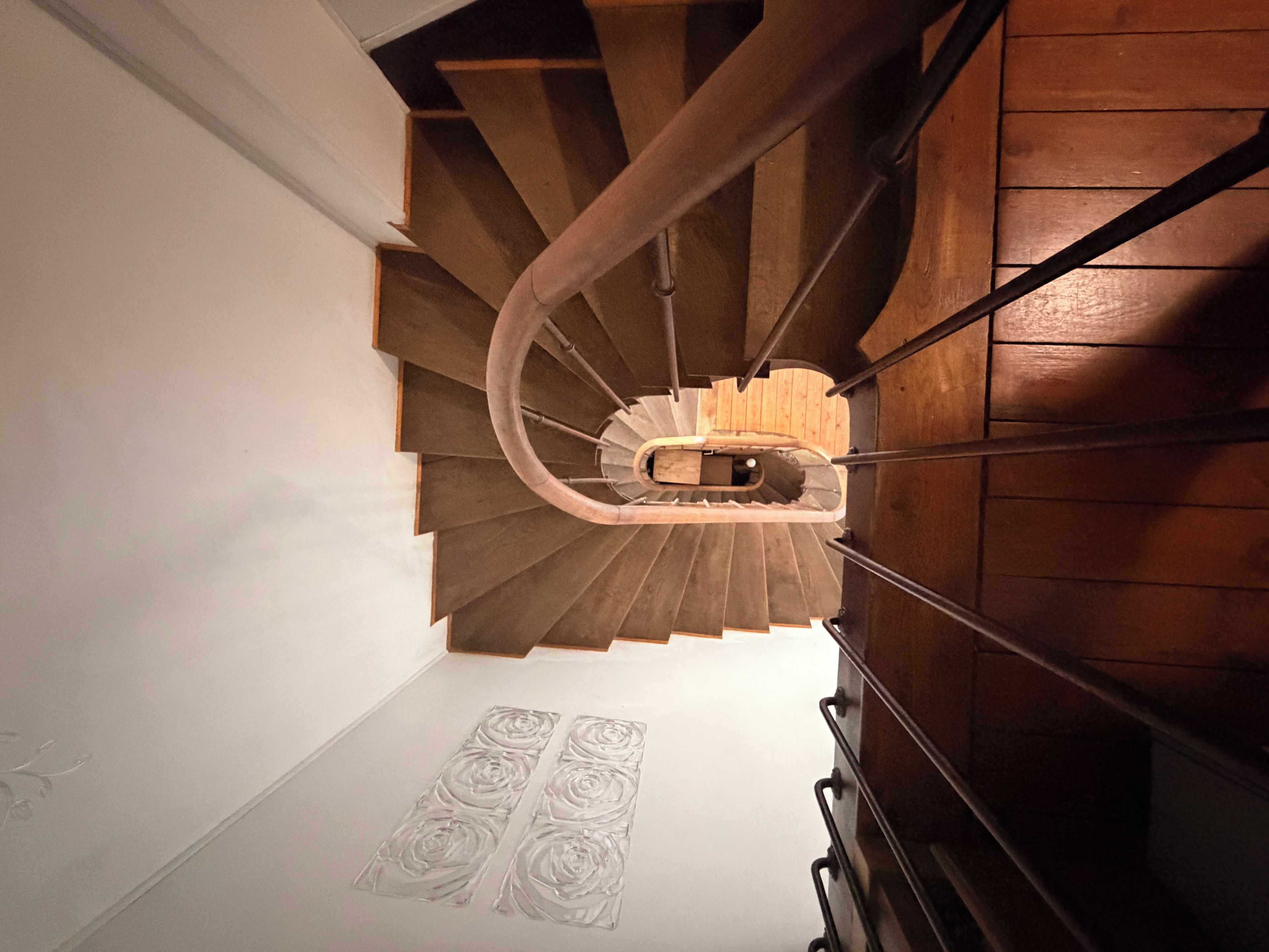 Un escalier en colimaçon avec des marches en bois et des rampes en métal.