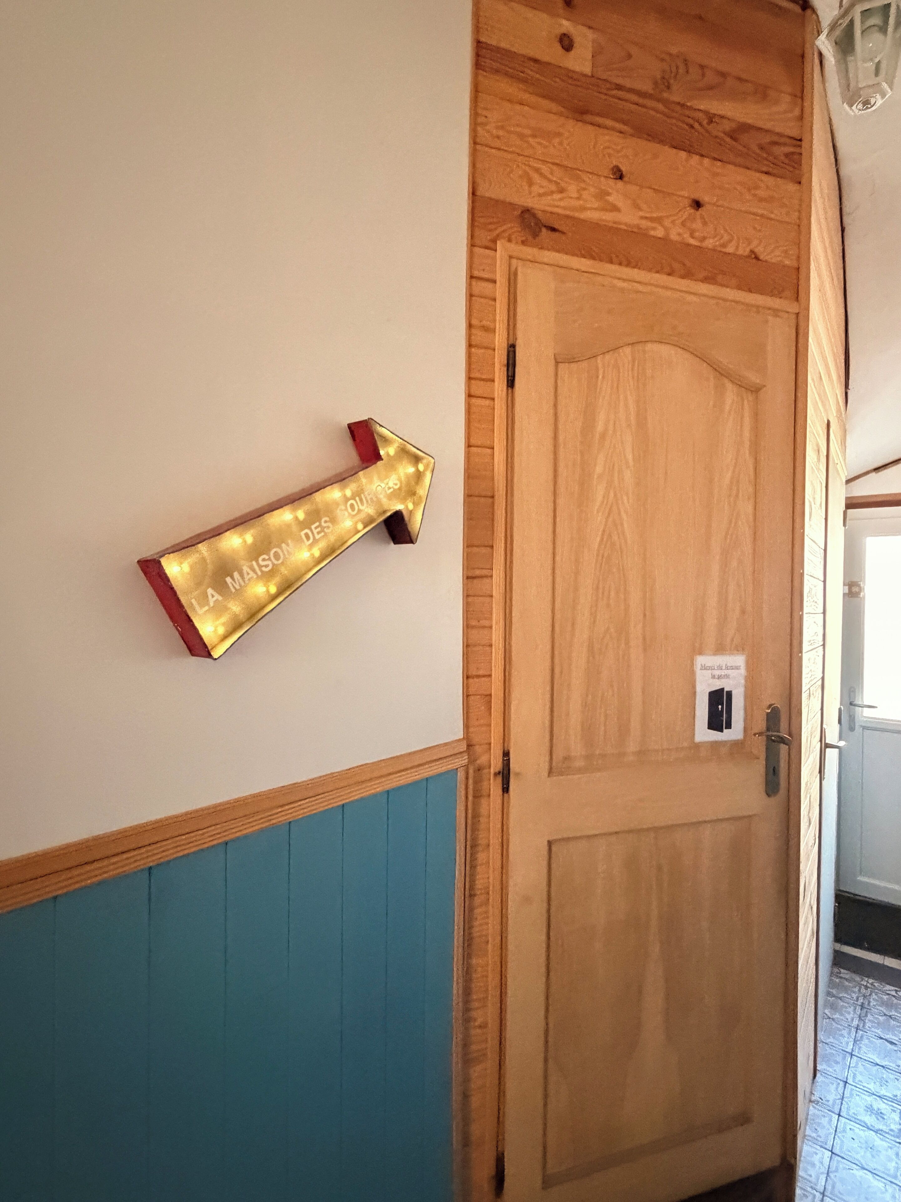 A wooden door with a light switch and a wall-mounted sign with an arrow.