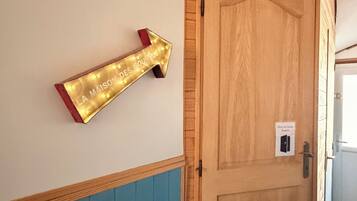 A wooden door with a light switch and a wall-mounted sign with an arrow.