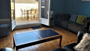 A room with a sliding glass door leading to an outdoor patio, a dark-colored sofa, a small table, and a lamp.