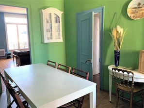 A dining area with a white table, chairs, a cabinet, and a door.
