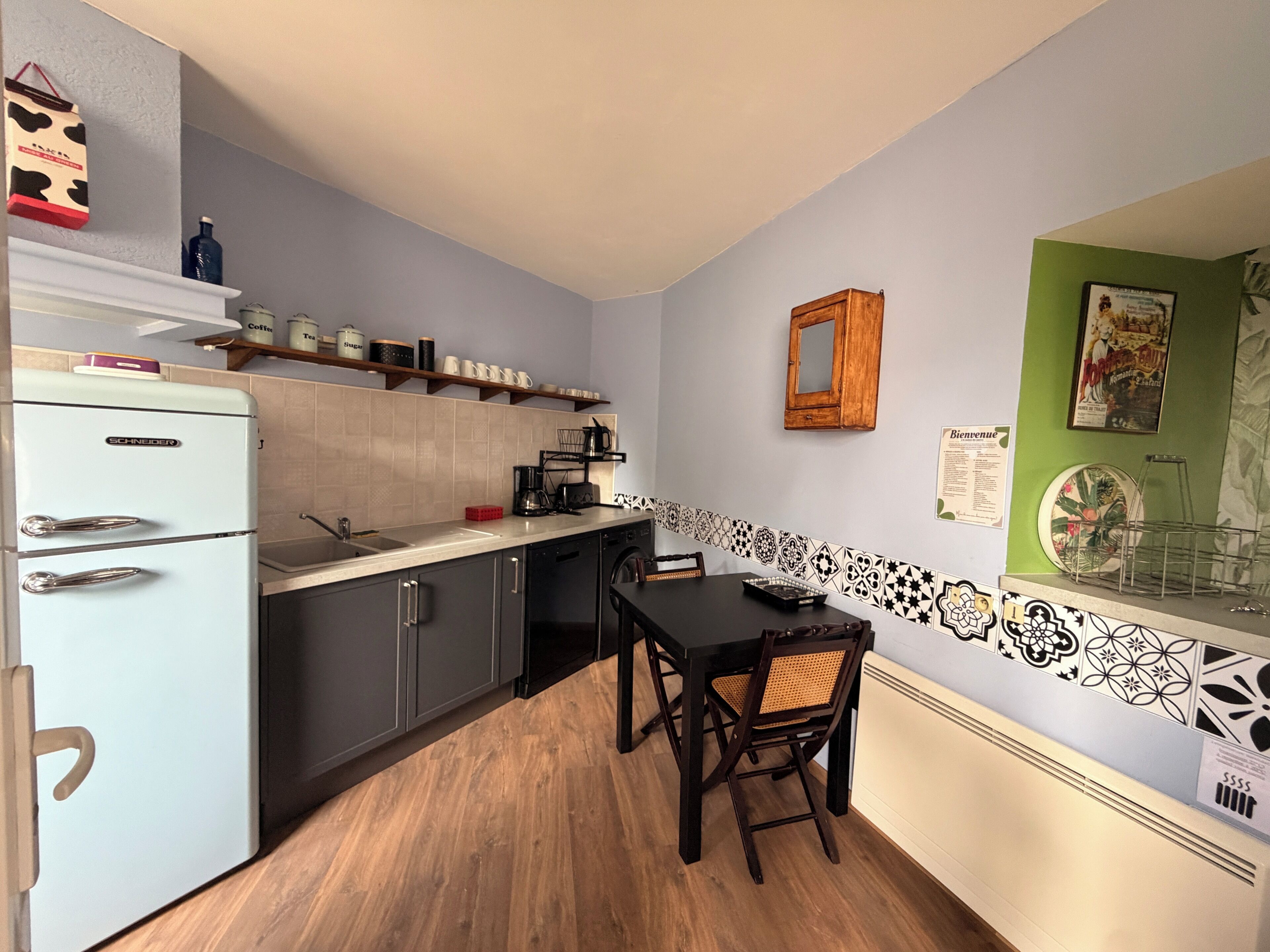 A compact kitchen with a white refrigerator, wooden cabinets, a black countertop, and a dining table with chairs.