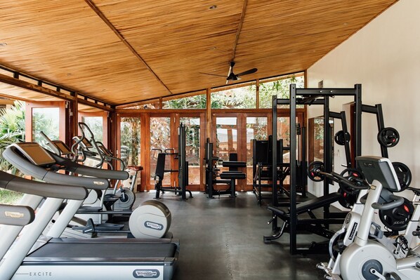 A gym with treadmills, weight machines, and a ceiling fan. - Heaven Restaurant and Boutique Hotel (Kigali)