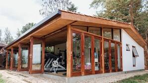 A modern building with a sloped roof, large glass doors, and a treadmill inside. - Heaven Restaurant and Boutique Hotel (Kigali)