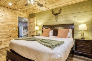 Ein Schlafzimmer mit Holzvertäfelung, einem Bett, Nachttischen und einem an der Wand befestigten Hirsch-Dekoration.