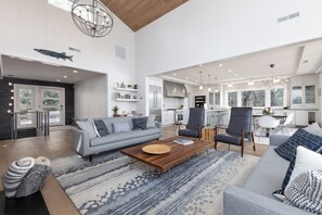 A spacious living area with a grey sofa, a wooden coffee table, and a patterned rug. - Upscale cozy retreat on Lake Glenville with private dock, kayaks, deck & fire pit. Sleeps 12. (Cullowhee)