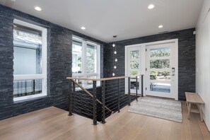 A modern interior with a staircase, dark stone walls, large windows, and a wooden bench. - Upscale cozy retreat on Lake Glenville with private dock, kayaks, deck & fire pit. Sleeps 12. (Cullowhee)