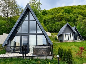 A modern, triangular-roofed building with a glass facade, surrounded by lush greenery.