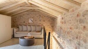 A cozy attic room with a stone wall, a sofa, and a round coffee table.