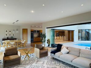A spacious living area with a large sofa, a dining table, and a kitchen in the background. - The Dominion Estate  Private Indoor Pool (McLean)