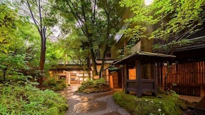 Ein traditioneller japanischer Garten mit Kieswegen, hölzernen Bauten und üppiger Vegetation.