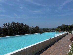 Ein Schwimmbecken mit klarem Wasser, umgeben von einer Holzterrasse und Bäumen.