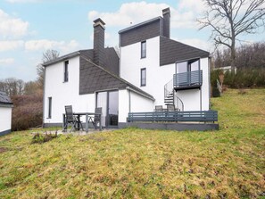 A modern two-story house with a balcony, a patio with outdoor furniture, and a grassy yard. - 4 Person Holiday Park Home in Dienstweiler (Oberhambach)
