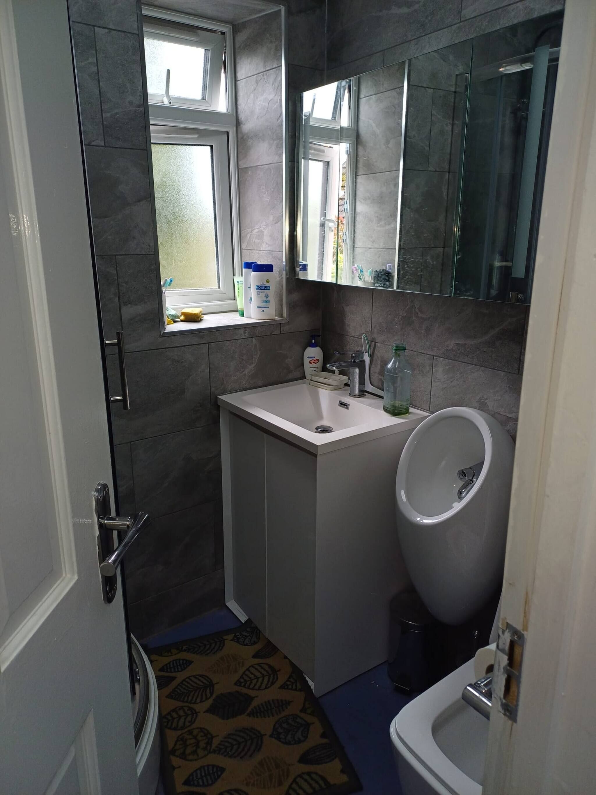 A compact bathroom with a window, a sink, a toilet, and a mirror.